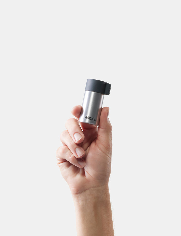 Matador Waterproof Travel Canister - 40ml - hand holding a silver and black container against a white background