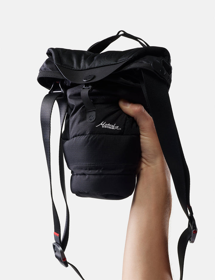 Matador Camera Base Layer 2.0 - black camera base layer held by a hand on a light gray background
