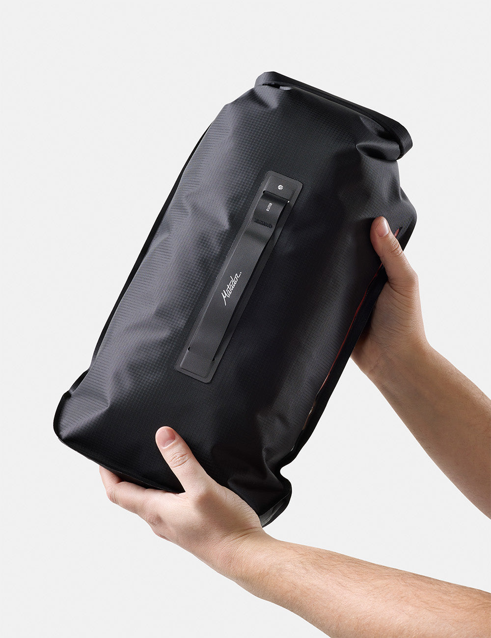 Matador FlatPak Drybag 8L (V2) in Black - black dry bag held by a person against a light gray background
