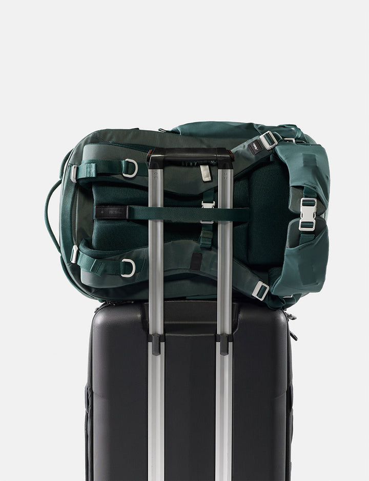 Matador 35L Global Travel Pack in Juniper - green backpack on top of a black suitcase with a white background
