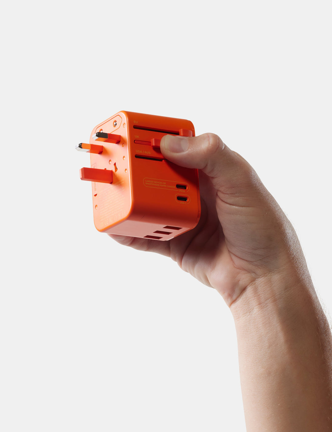 Matador Global Travel Adapter in Orange - hand holding an orange travel adapter against a white background