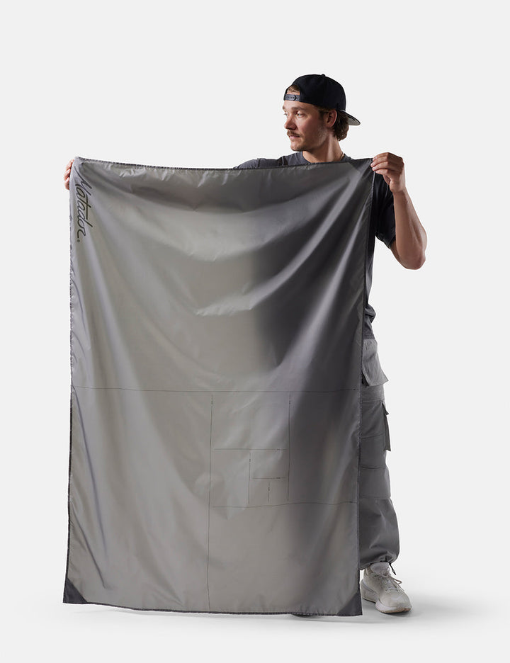 Matador Pocket Blanket™ 4.0 - 160 x 110cm in Black - person holding a large gray fabric against a white background