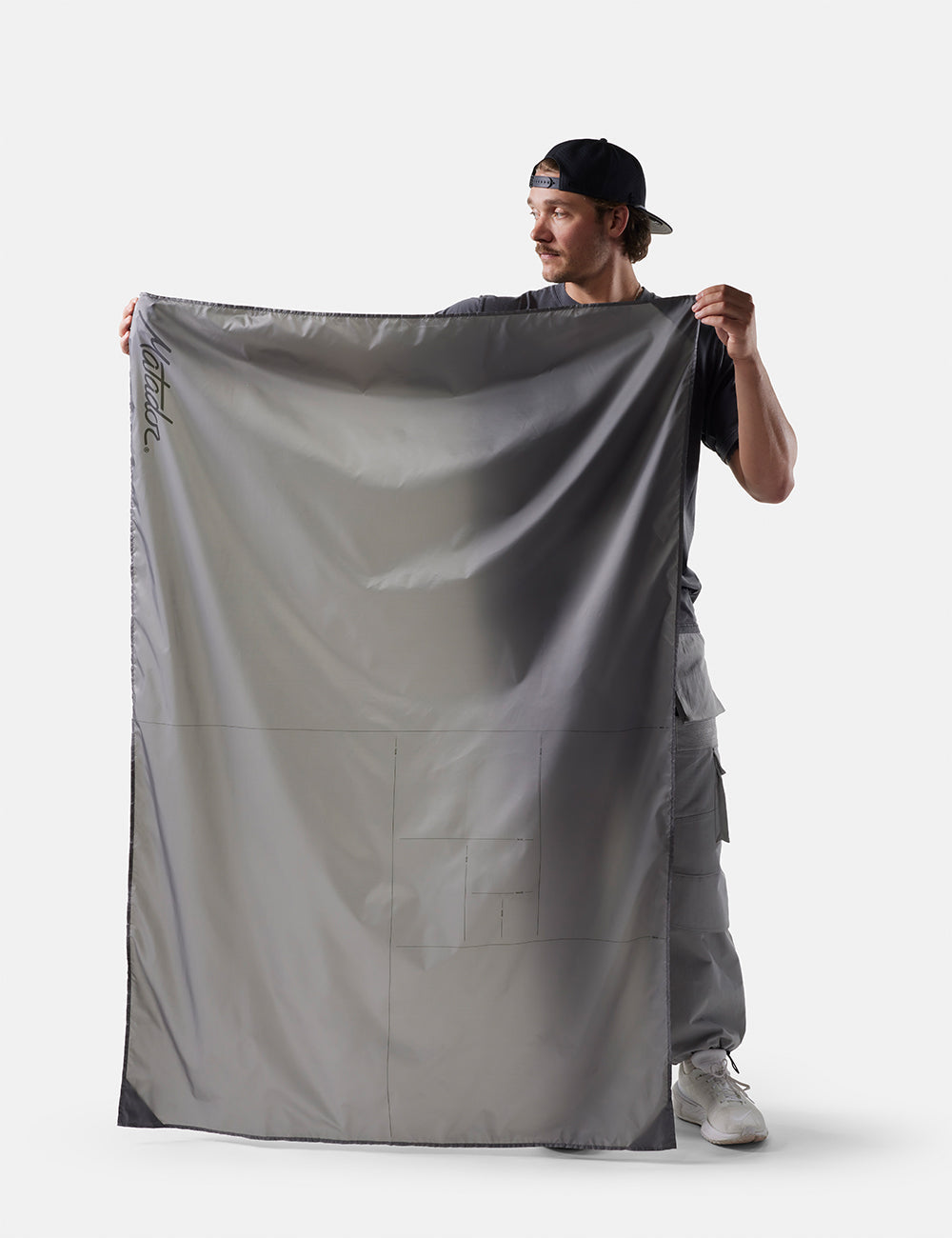 Matador Pocket Blanket™ 4.0 - 160 x 110cm in Blue - person holding a large gray fabric against a white background
