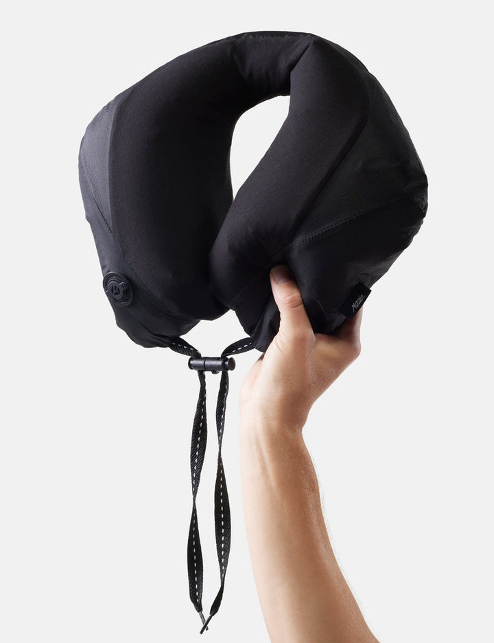 Matador Blackout Travel Pillow - black travel neck pillow held by a hand against a white background