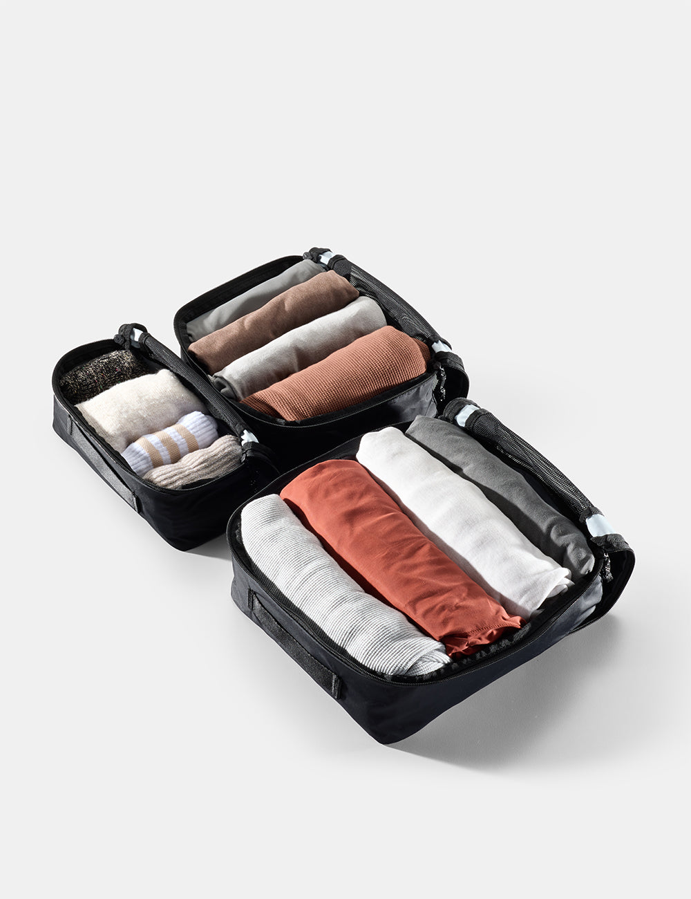 Matador Packing Cube Set (V2) in Black - compact travel organizer with neatly folded clothes on a light gray background