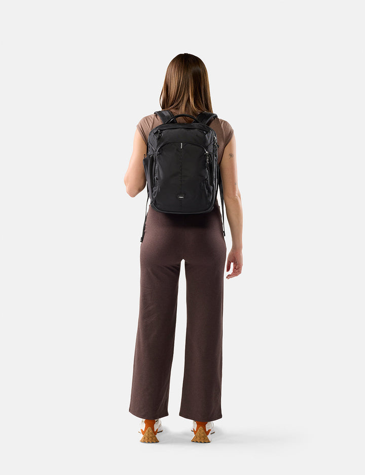 Matador 18L Personal Item Travel Pack in Black - person wearing a black backpack on a white background
