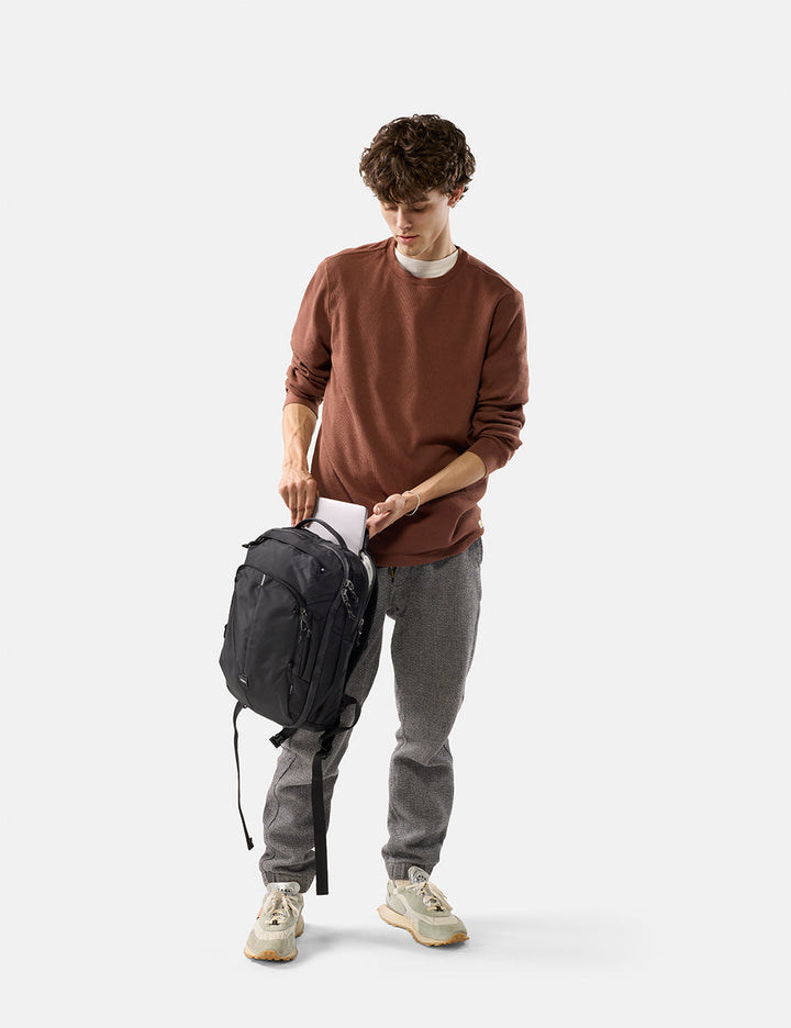 Matador 18L Personal Item Travel Pack in Black - man holding a black backpack on a white background