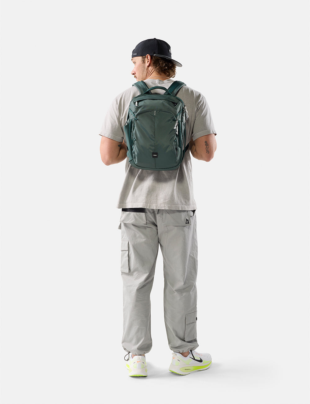 Matador 18L Personal Item Travel Pack in Juniper - person wearing a green backpack on a white background