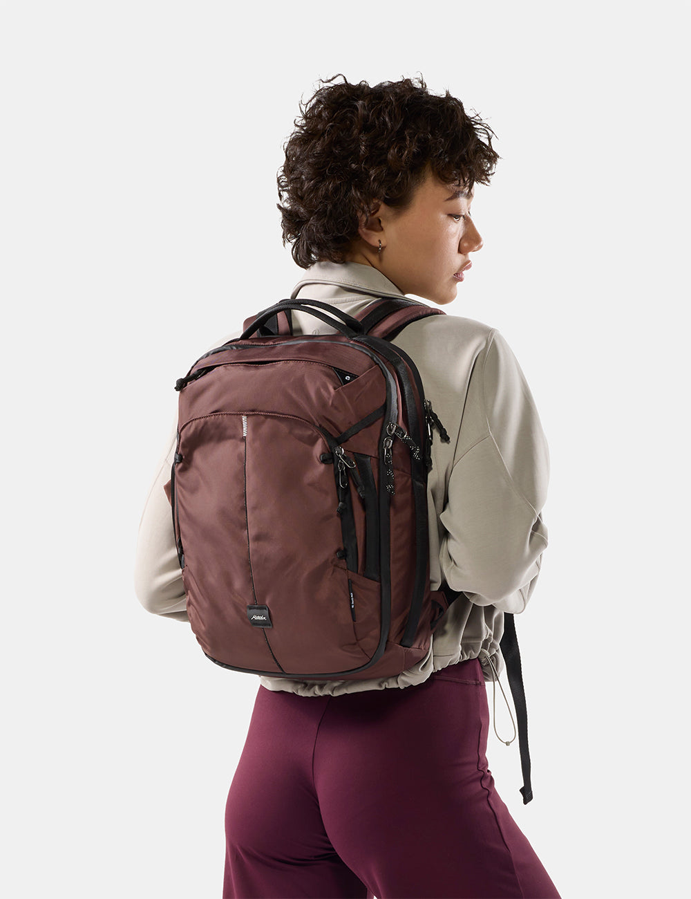 Matador 18L Personal Item Travel Pack in Garnet - person on light gray background wearing a small garnet backpack