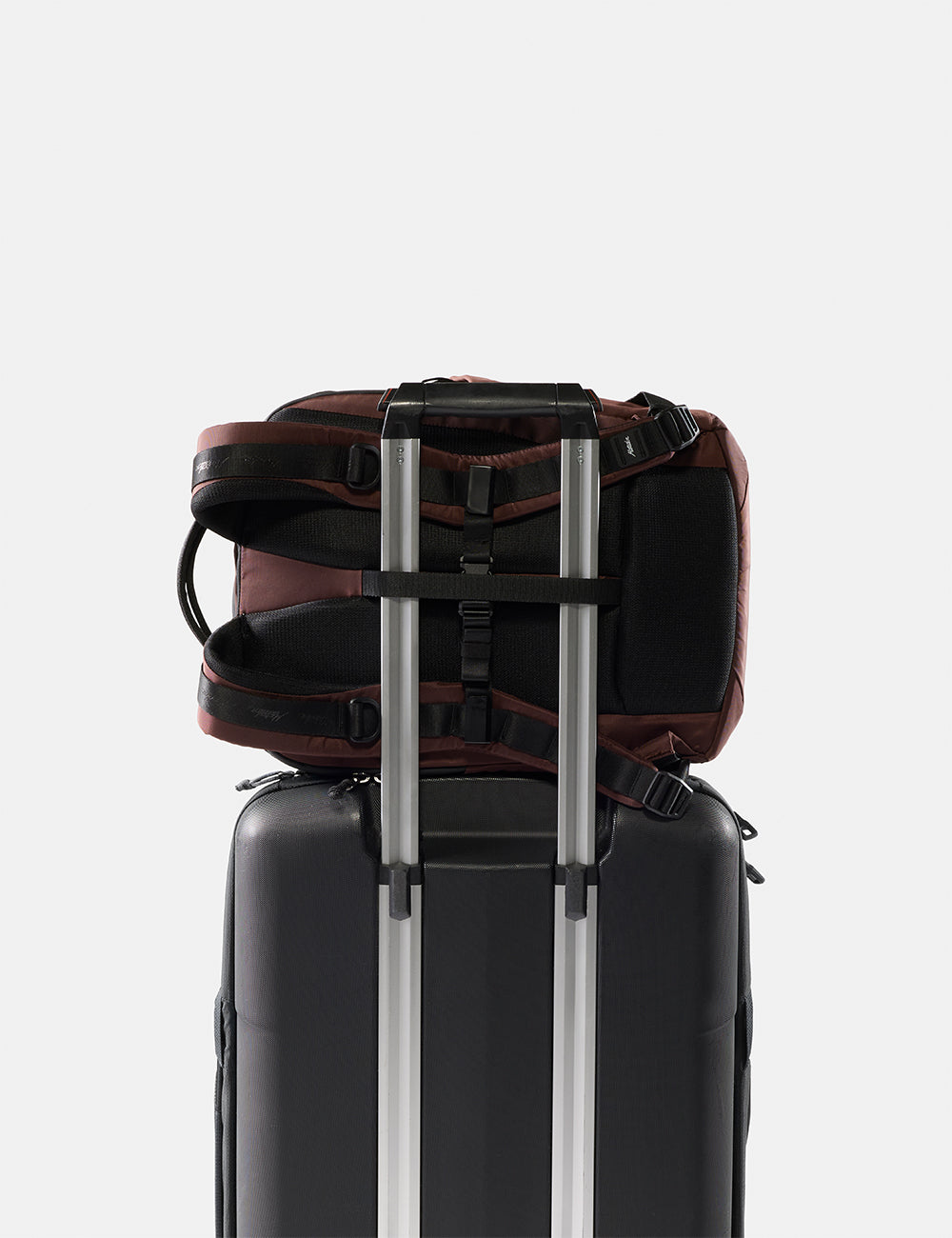 Matador 18L Personal Item Travel Pack in Garnet - backpack attached to a suitcase on a light gray background