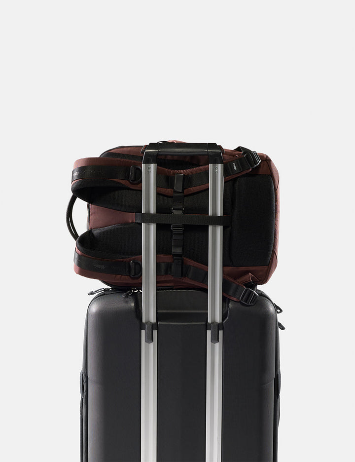 Matador 18L Personal Item Travel Pack in Garnet - backpack attached to a suitcase on a light gray background