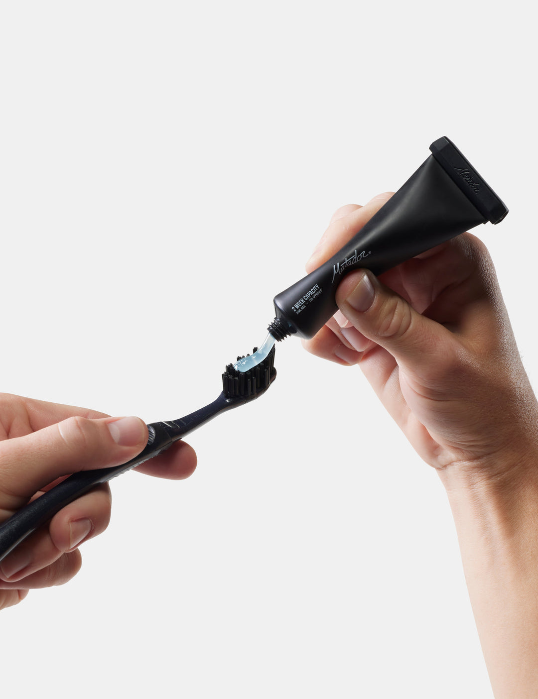 Matador Refillable Toothpaste Tubes - 2 Pack - person applying toothpaste to a black toothbrush on a white background