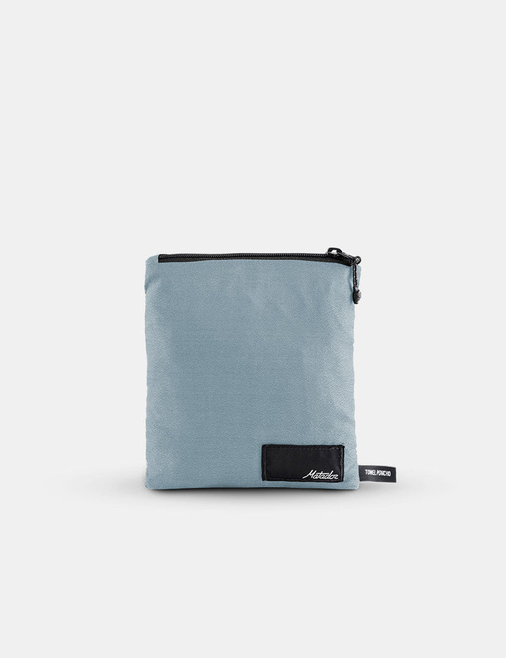 Matador NanoDry™ Packable Towel Poncho in Slate Blue - light blue pouch with a black zipper and visible brand logo on a white background